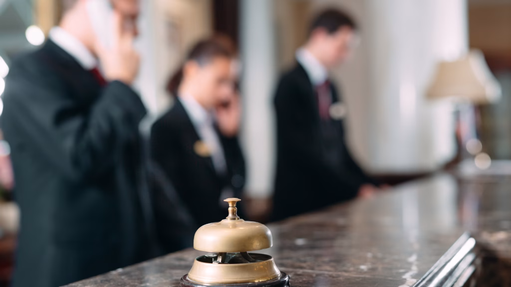 Hotelserviceglocke auf der Rezeption mit Personal im Hintergrund